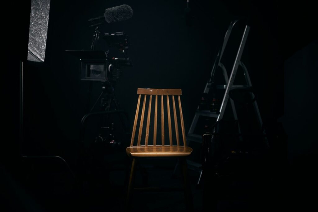 Silla de madera iluminada en un plató oscuro antes de rodar una película biográfica