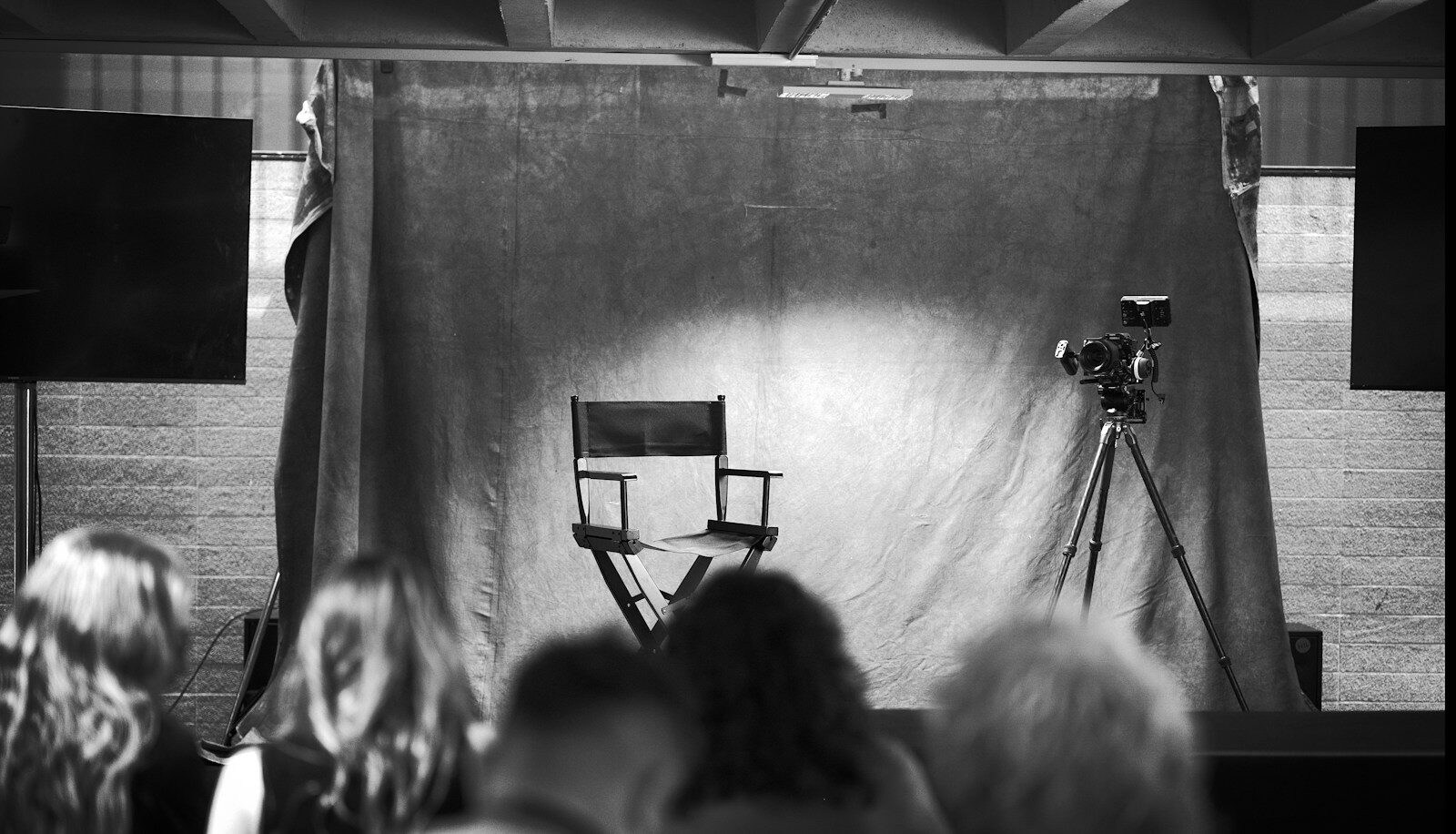 Rodaje en blanco y negro de un biopic, con la silla del director y el público mirando la escena
